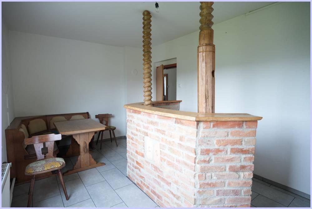 Traditioneller Essbereich mit Holztisch, Eckbank und einem Bartresen aus Ziegelmauerwerk.