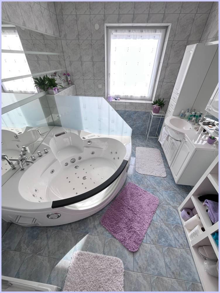 Geräumiges Badezimmer mit Whirlpool-Badewanne, Dachfenster und hellblauen Fliesen.