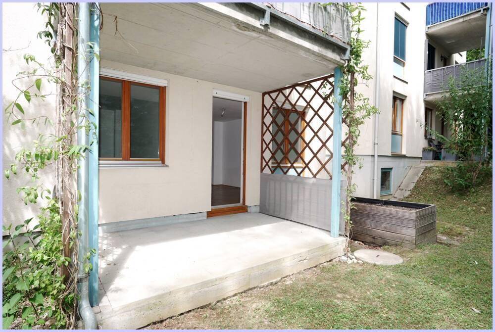 Überdachte Terrasse mit Gitterrankhilfe und Zugang zu einem kleinen Gartenbereich.