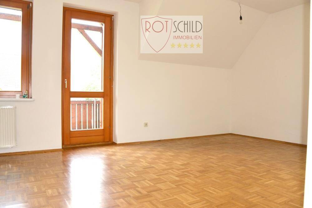 Geräumiges Schlafzimmer mit Parkettboden, Dachschräge und viel natürlichem Licht.