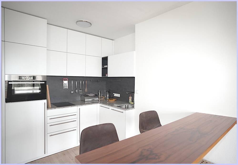 Moderne Einbauküche mit weißen Schränken und integriertem Essbereich an der Theke.