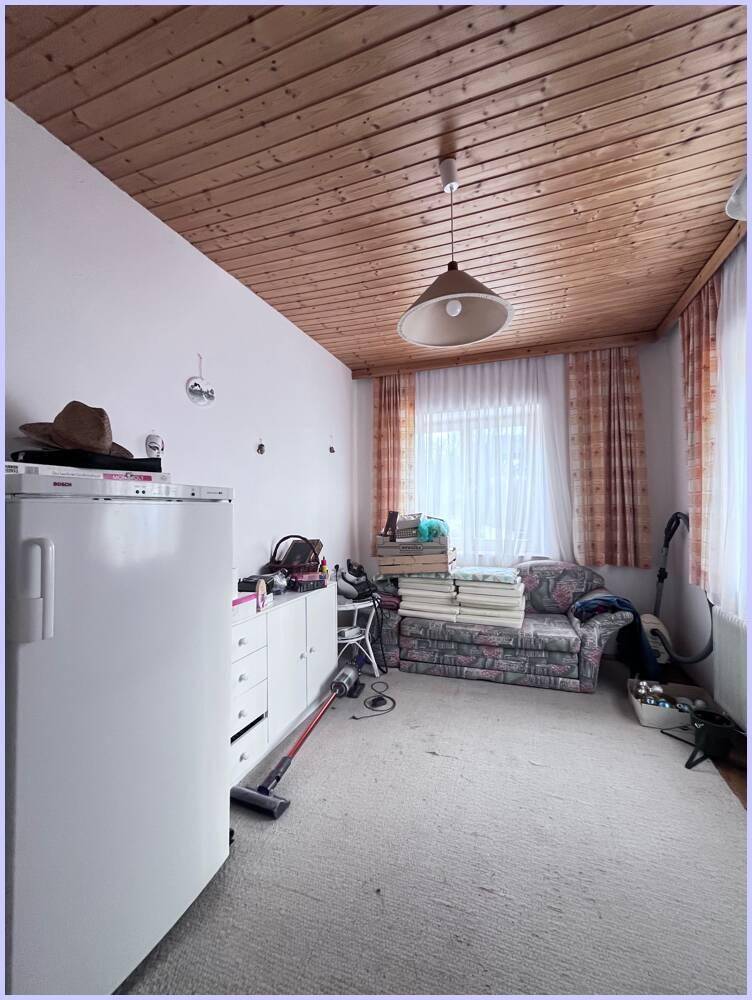 Funktionaler Raum mit Teppichboden, Holzdecke und einem Fenster, der als Abstell- oder Hobbyraum genutzt werden könnte.