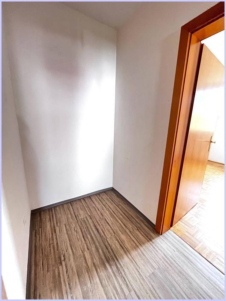 Leerer Raum mit Laminatboden und weiß gestrichenen Wänden, bereit zur individuellen Gestaltung.