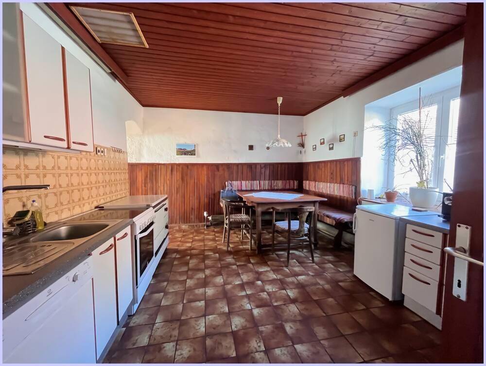 Traditionelle Wohnküche mit Terrakottafliesen, Holzdecke und einer gemütlichen Eckbank für gemeinsame Mahlzeiten.