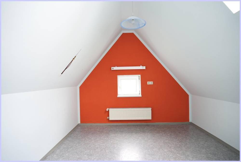 Dachzimmer mit schrägen Wänden, einer leuchtend orangefarbenen Akzentwand und Fenster.
