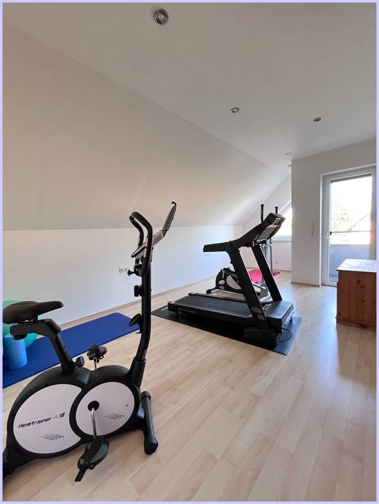 Fitnessraum im Dachgeschoss mit Trainingsgeräten, hellem Boden und natürlichem Lichteinfall.