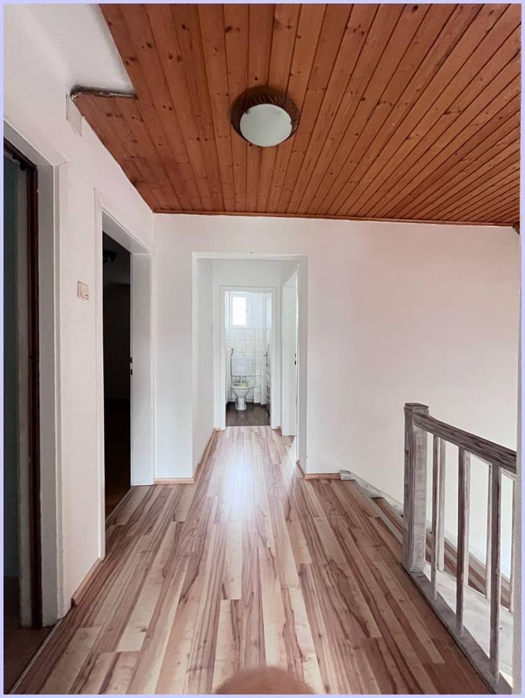 Heller Flur mit Holzdecke und Laminatboden, führt zu weiteren Räumen.