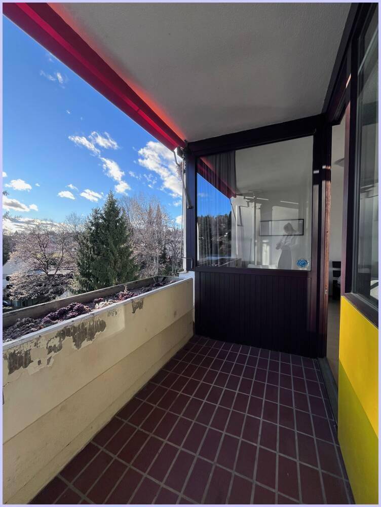 Sonniger Balkon mit Fliesenboden und weitem Blick auf die umliegende Natur.
