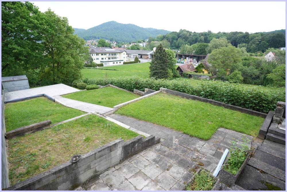 Terrassierter Gartenbereich mit Rasen und Blick auf die umliegende Landschaft und Häuser.