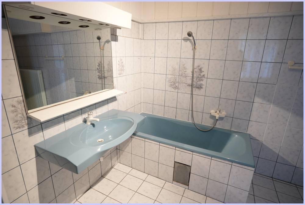 Detailansicht des Badezimmers mit blauer Badewanne und passendem Waschbecken.