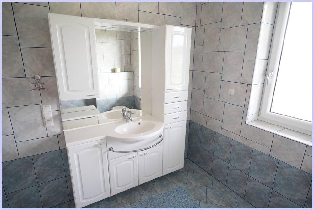 Badezimmer mit Waschtisch, Spiegelschrank und blauen sowie weißen Fliesen.