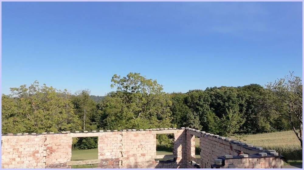 Nahaufnahme der Ziegelwände einer Ruine mit weitem Blick auf die umliegende grüne Landschaft.