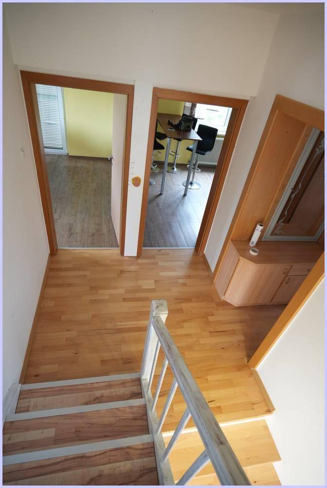 Heller Treppenabsatz mit Holzfußboden und Zugängen zu weiteren Räumen.