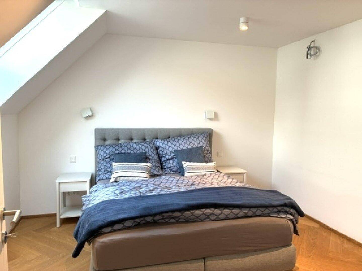 Gemütliches Schlafzimmer im Dachgeschoss mit Doppelbett, Dachschräge und Parkettboden.