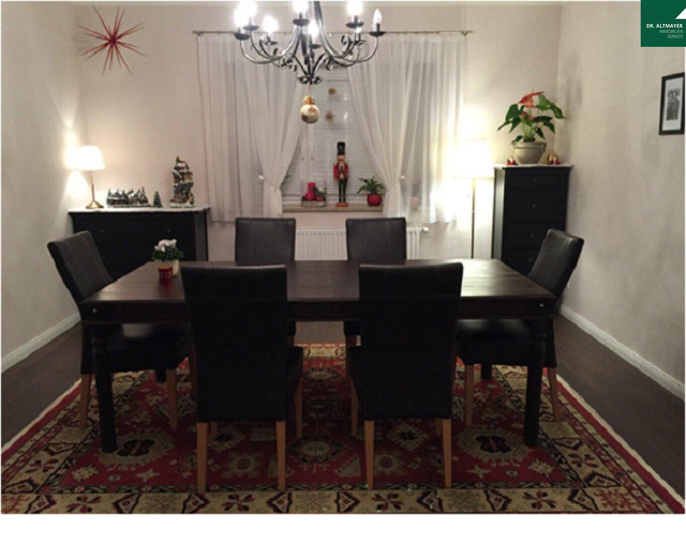 Gemütlicher Essbereich mit großem Holztisch, schwarzen Stühlen und festlicher Weihnachtsdekoration.