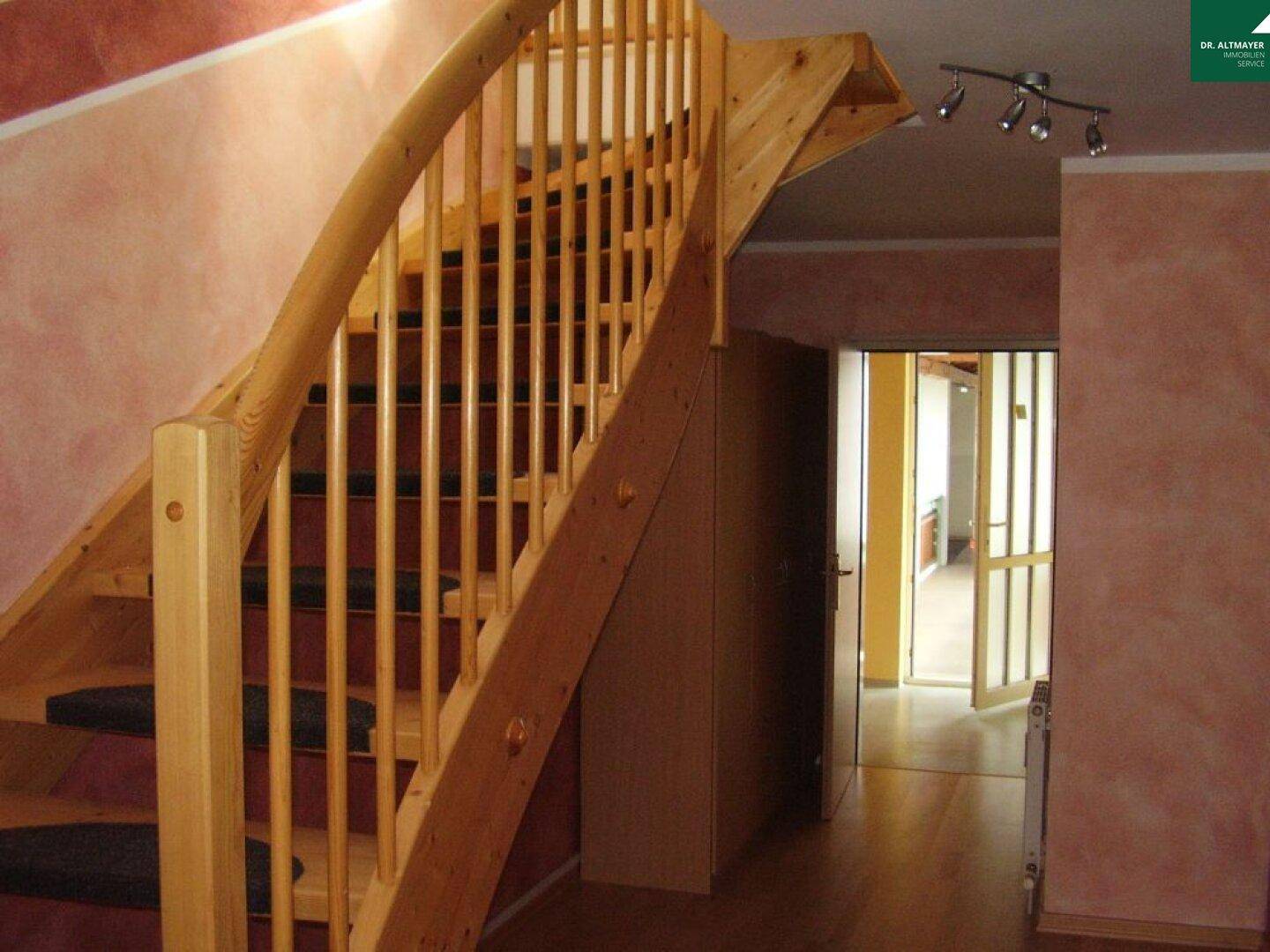 Heller Flur mit Holztreppe, die in die obere Etage führt, und Zugang zu weiteren Räumen.