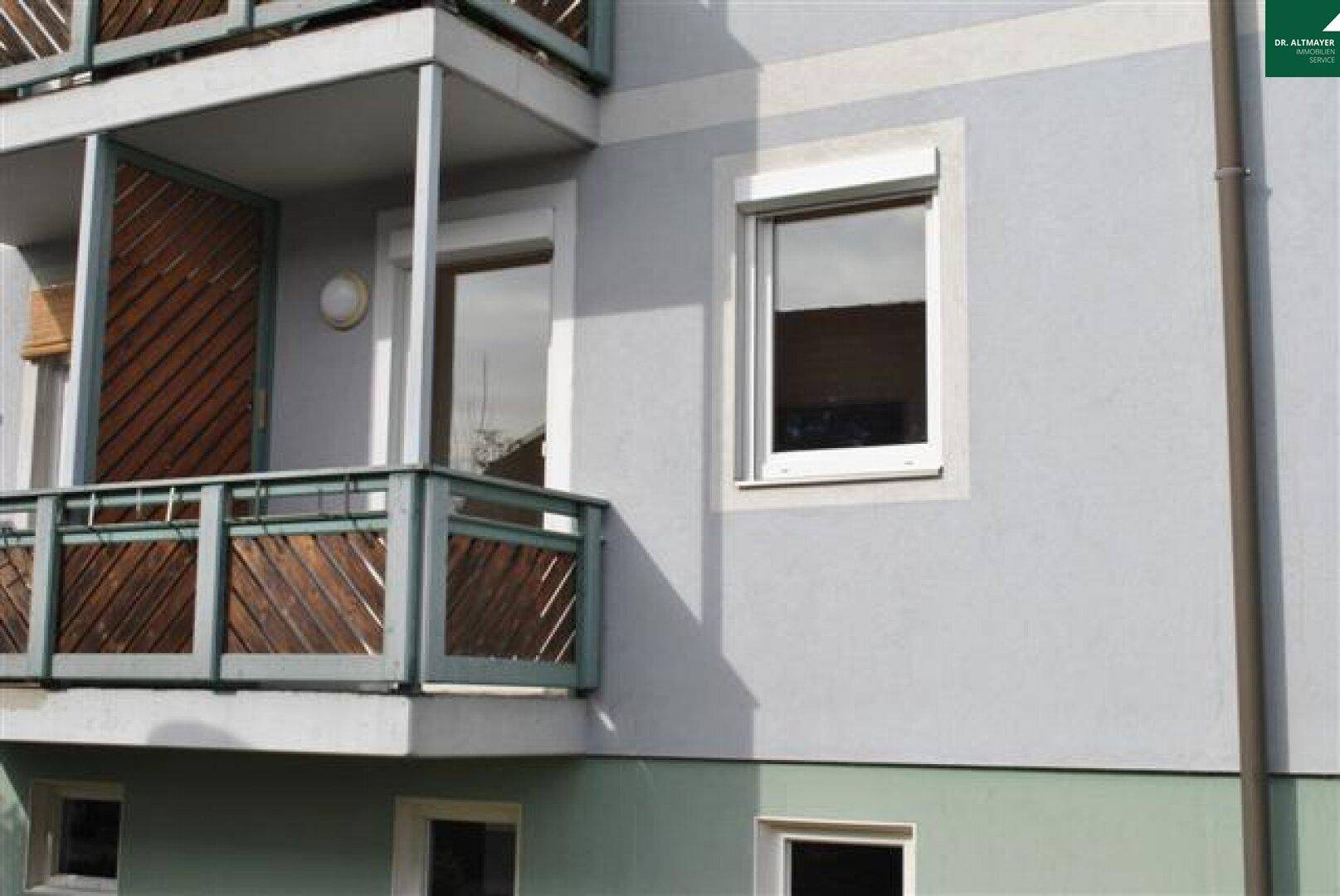 Außenansicht des Gebäudes mit einem Balkon und Rollläden an den Fenstern.