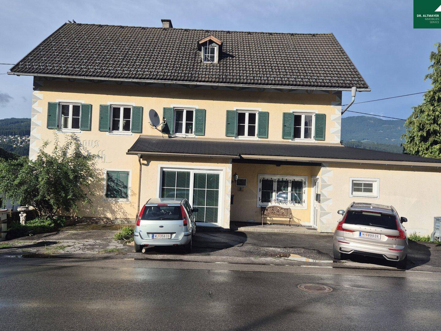 Vorderansicht des Hauses mit geparkten Autos und traditioneller Fassade.