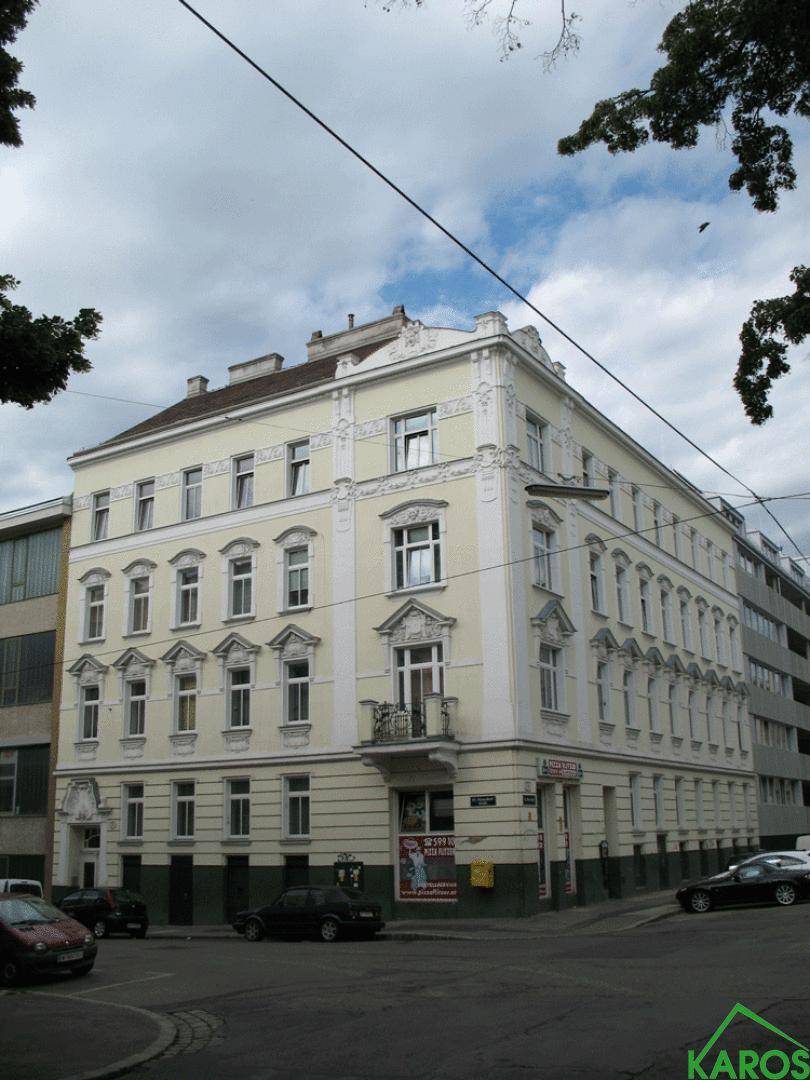 Historisches Eckgebäude mit klassischer Fassade, Stuckverzierungen und kleinem Balkon an einer Stadtstraße.