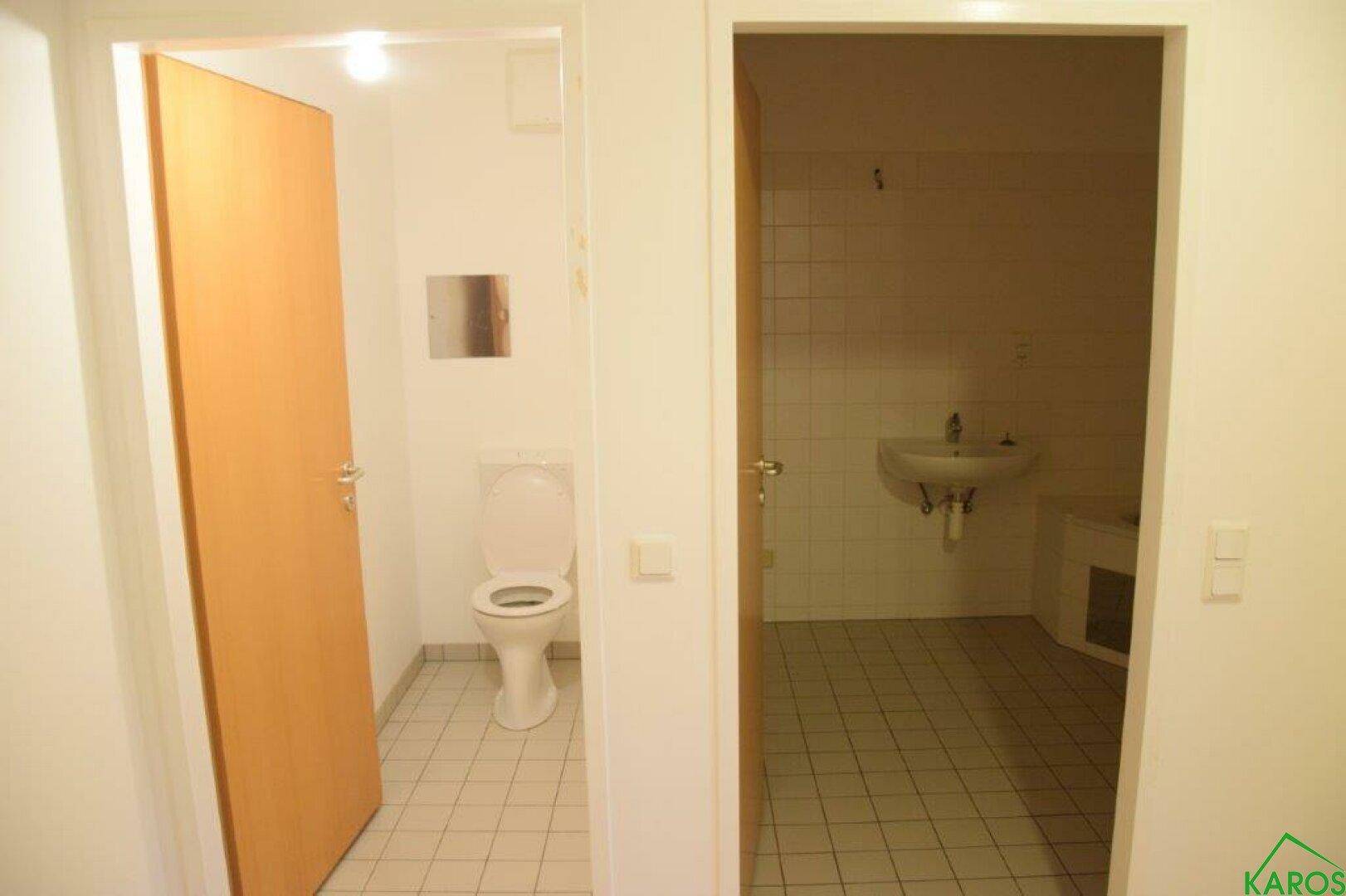 Blick auf zwei Türen, die zu einem Badezimmer und einer separaten Toilette führen.