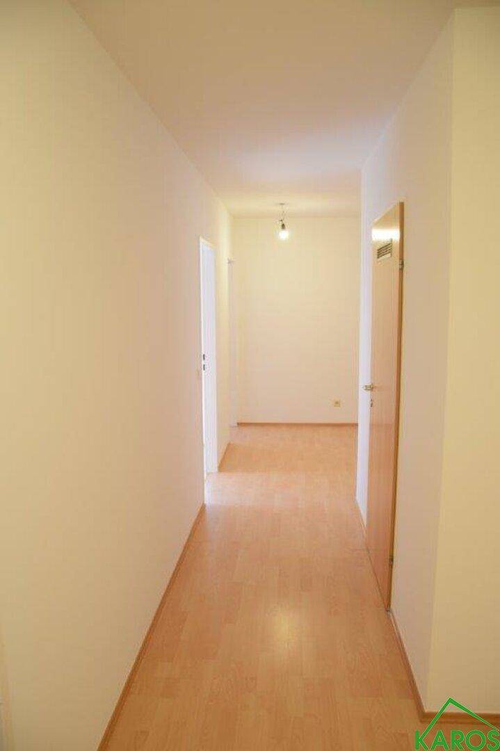Langer, heller Flur mit Laminatboden, der zu weiteren Zimmern führt.