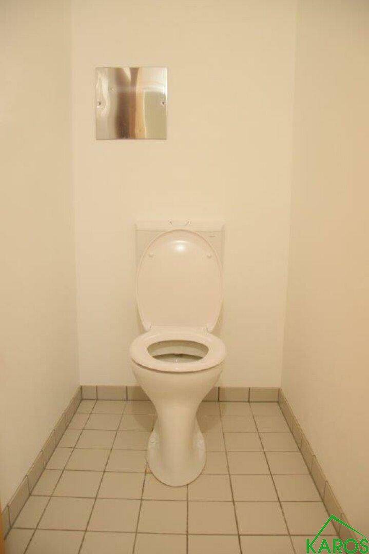 Separate Toilette mit Fliesenboden und weißer Keramik, in gutem Zustand.