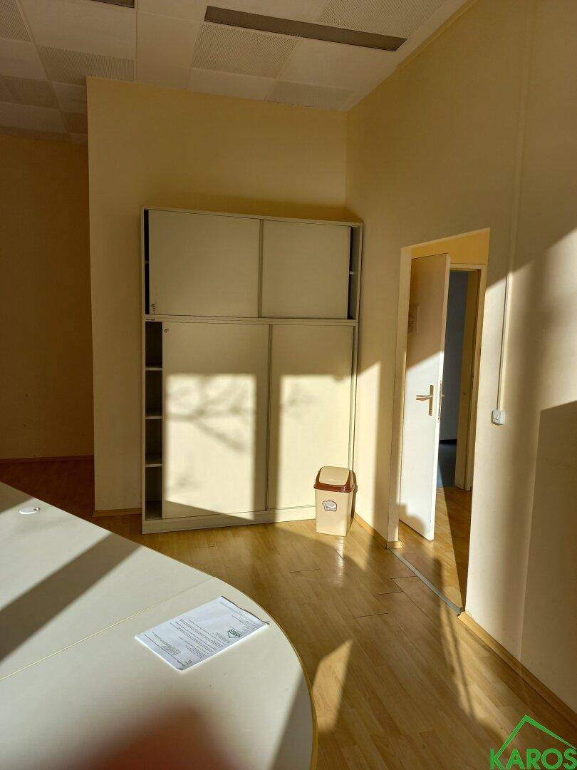 Bürobereich mit Einbauschränken, Holzboden und Zugang zu weiteren Räumen, hell und funktional.