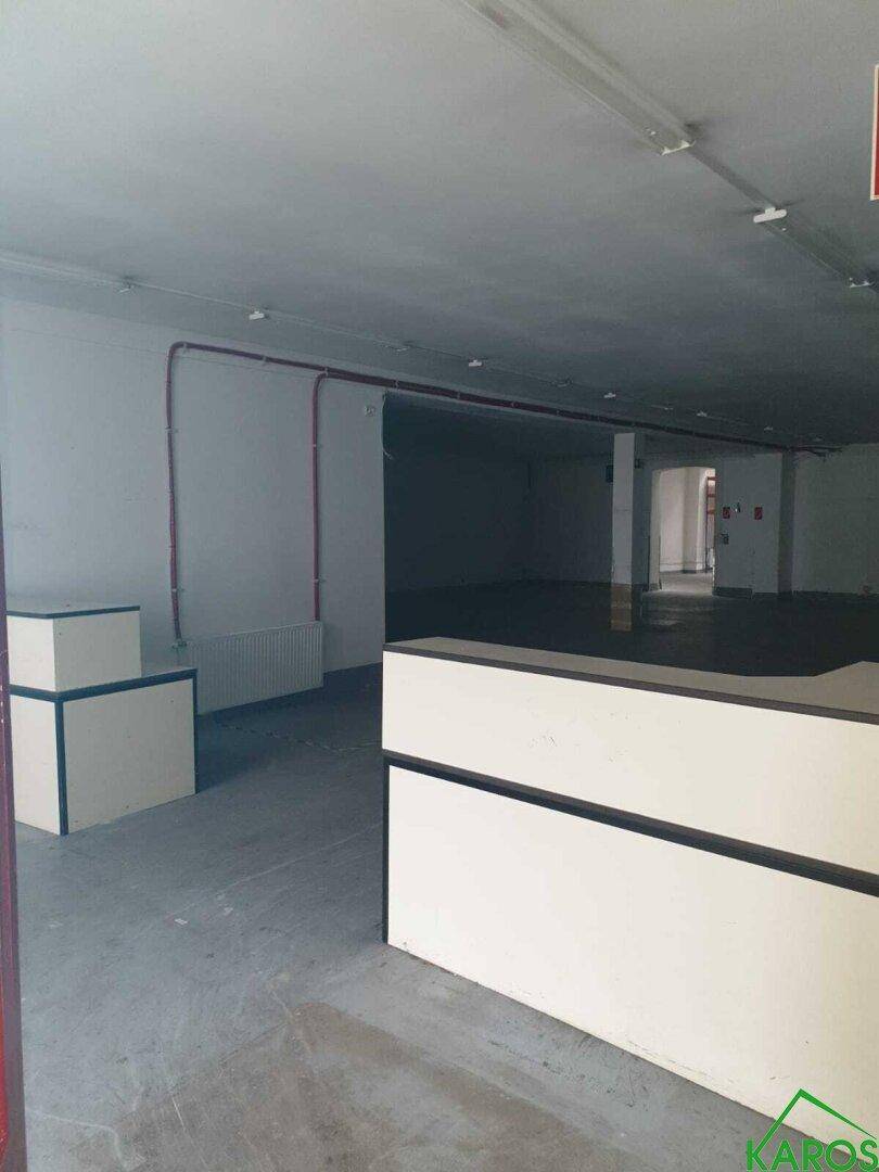 Geräumiger Gewerberaum mit Empfangstheke und sichtbaren Leitungen an den Wänden.