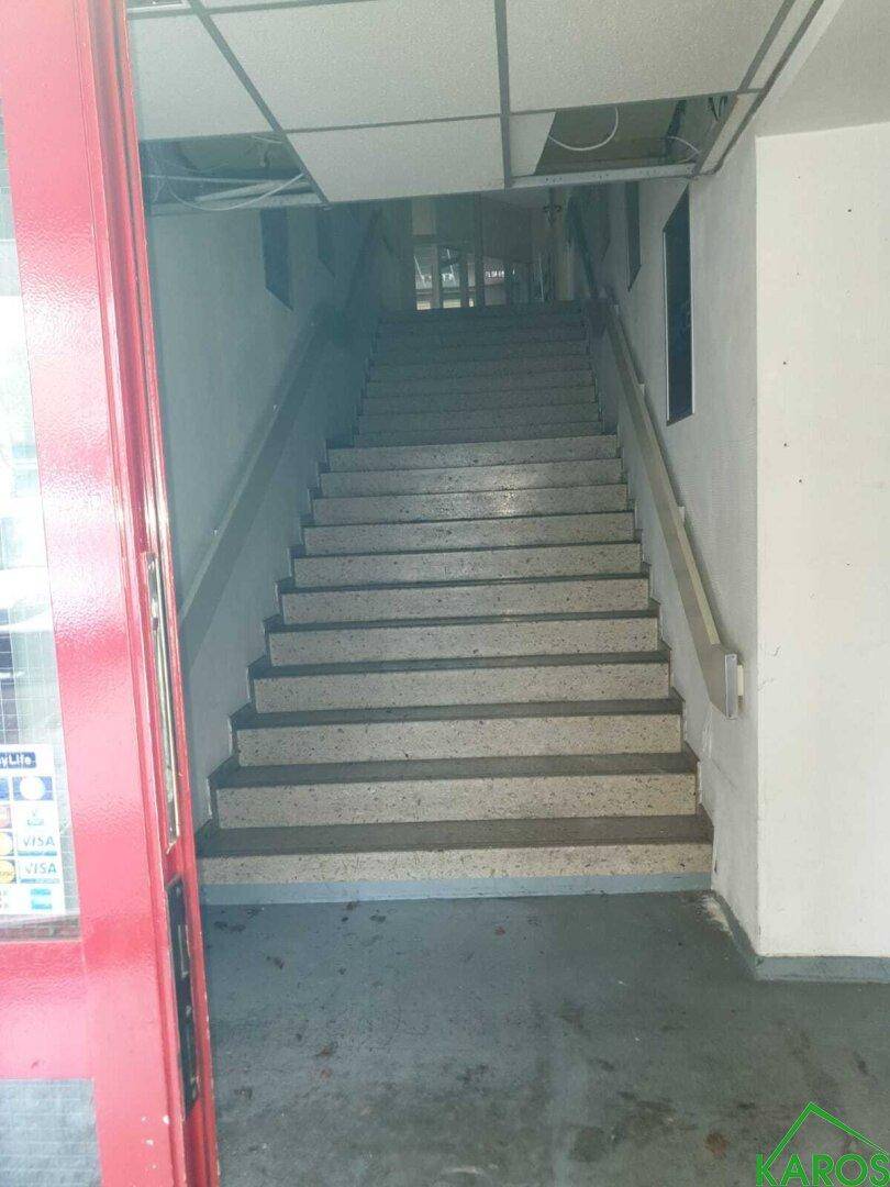 Treppenhaus mit Terrazzostufen und rotem Türrahmen, führt in die oberen Etagen.