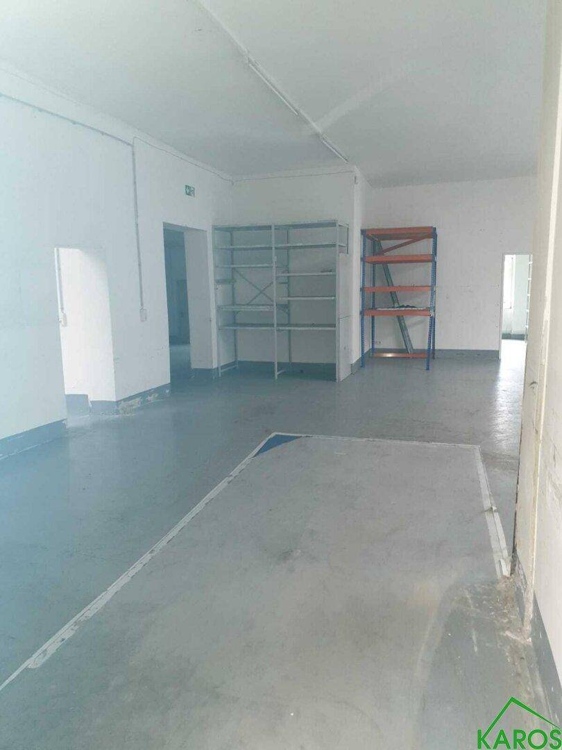 Geräumiger Lagerraum mit zwei verschiedenen Regalsystemen und grauem Boden.