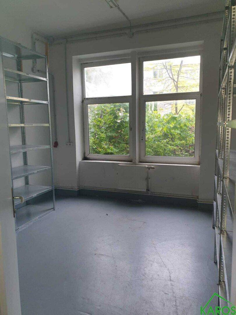 Kleiner Abstellraum mit großem Fenster, Blick ins Grüne und Metallregalen.
