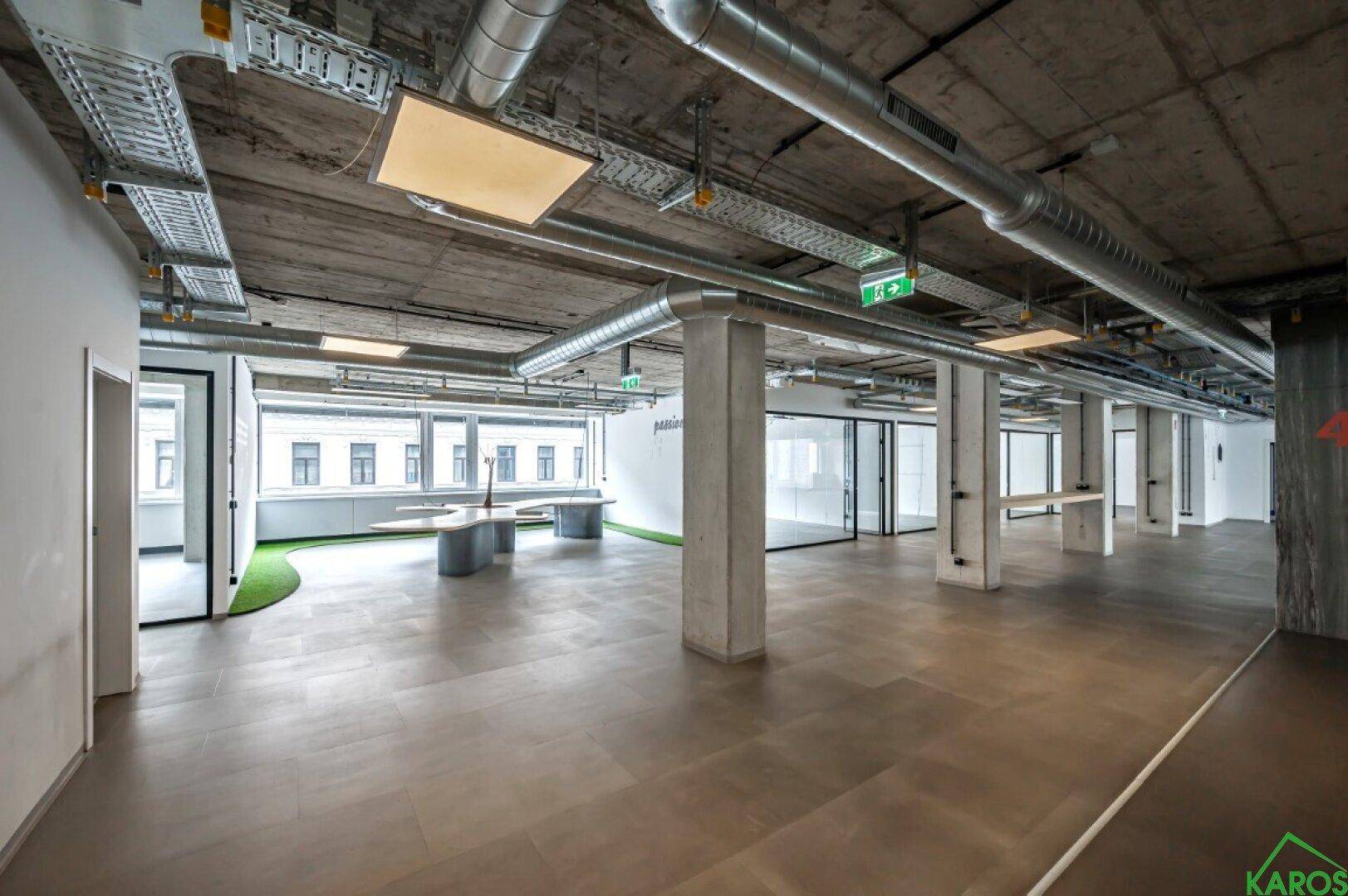 Großzügige, offene Bürofläche mit hohen Decken, Säulen und großen Fenstern.