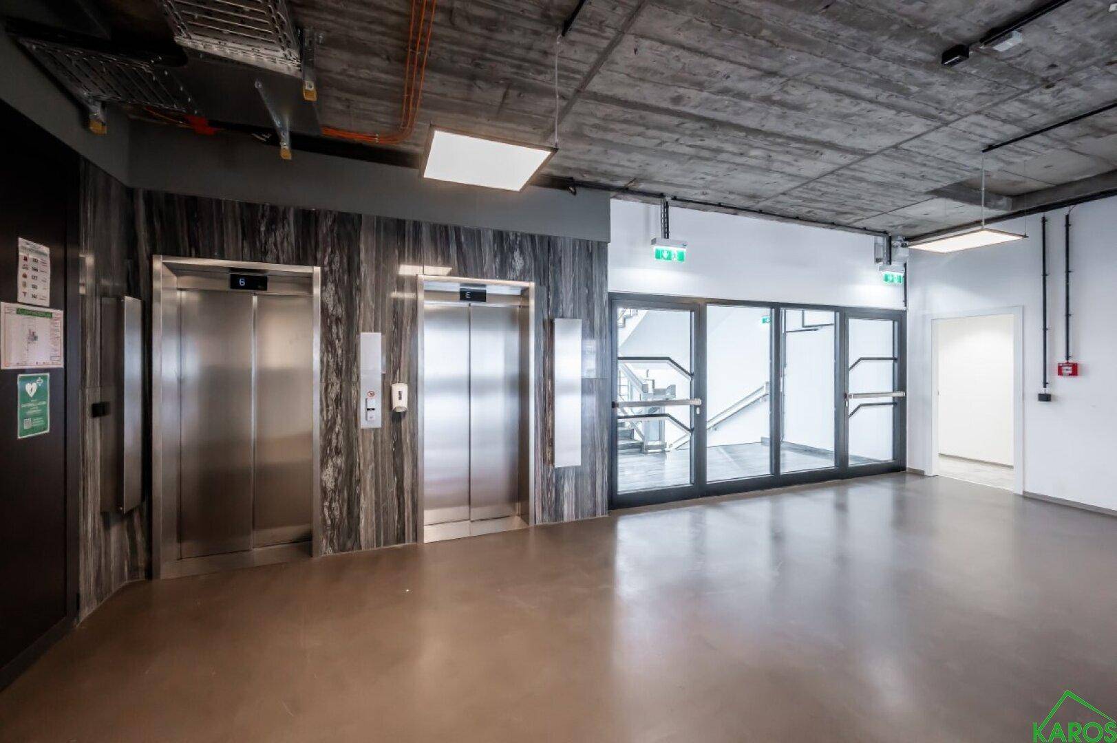 Moderner Empfangsbereich mit zwei Aufzügen und Zugang zu einem Treppenhaus.