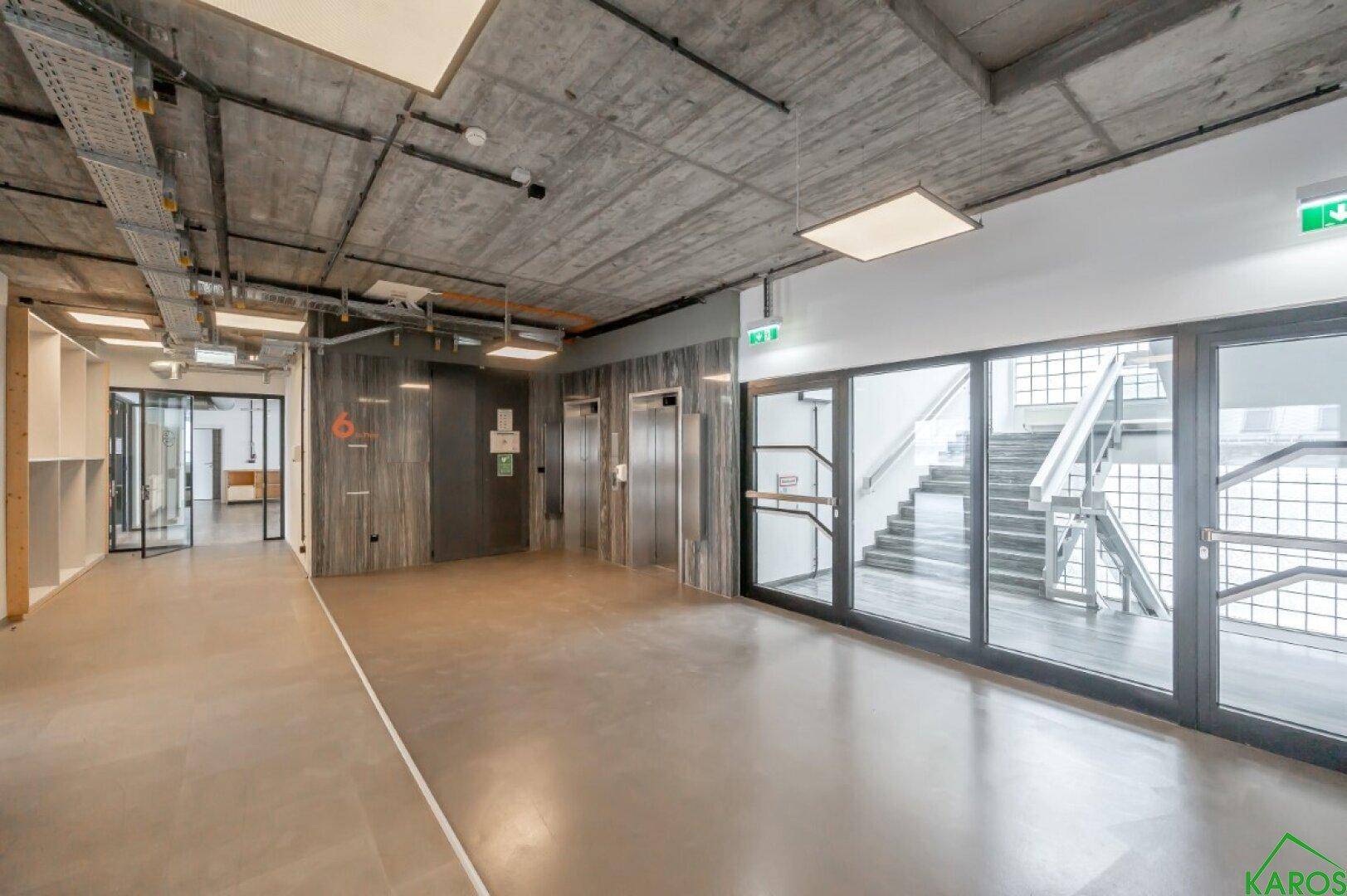 Eingangsbereich mit Aufzügen und einem Treppenhaus, gekennzeichnet durch industrielles Design.