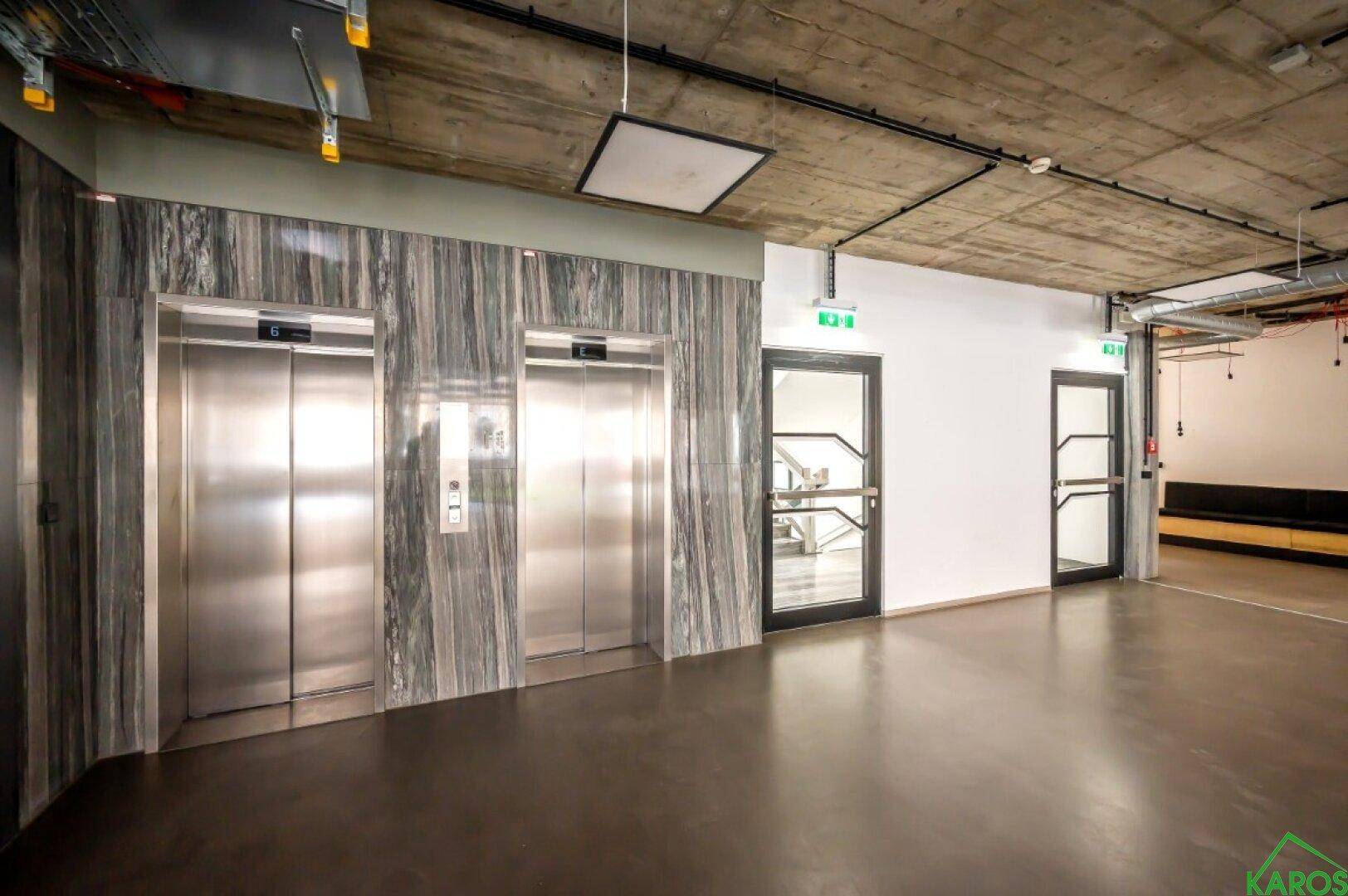 Moderner Eingangsbereich mit zwei Aufzügen und industriellem Design, gut beleuchtet.
