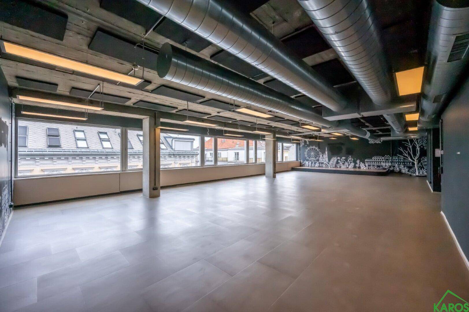 Offene Bürofläche mit Akustikpaneelen an der Decke und einer künstlerisch gestalteten Wand.