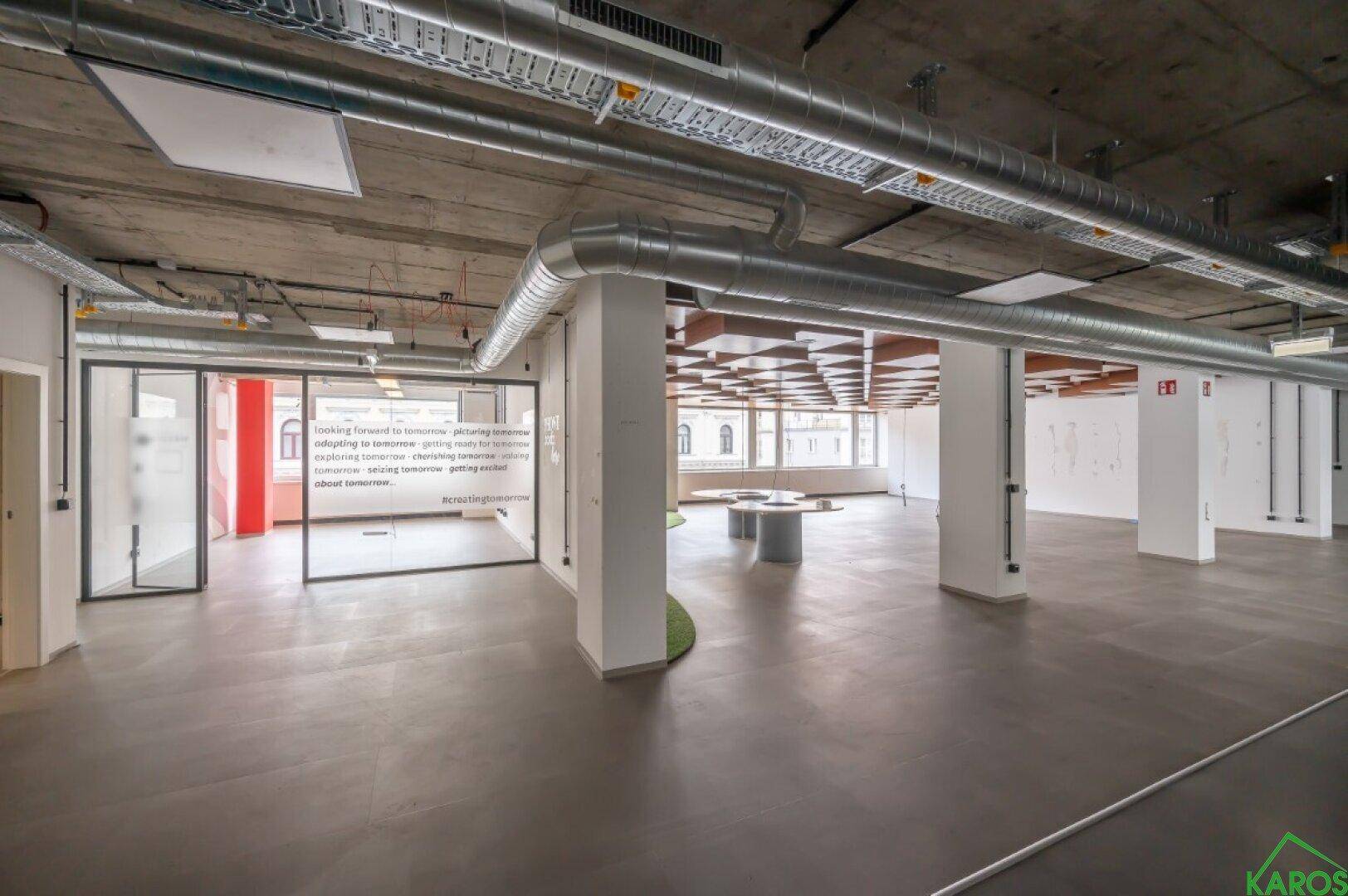 Großzügige Bürofläche mit freiliegenden Decken, Säulen und dekorativen Holzelementen an der Decke.