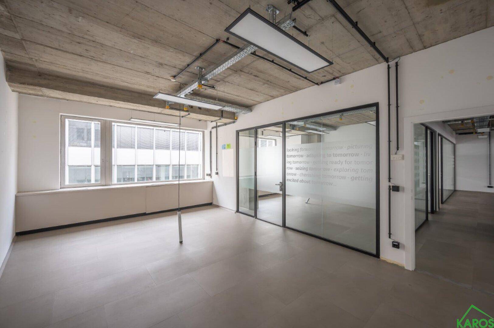 Helles Einzelbüro mit Glaswänden und einer großen Fensterfront, die viel Tageslicht bietet.