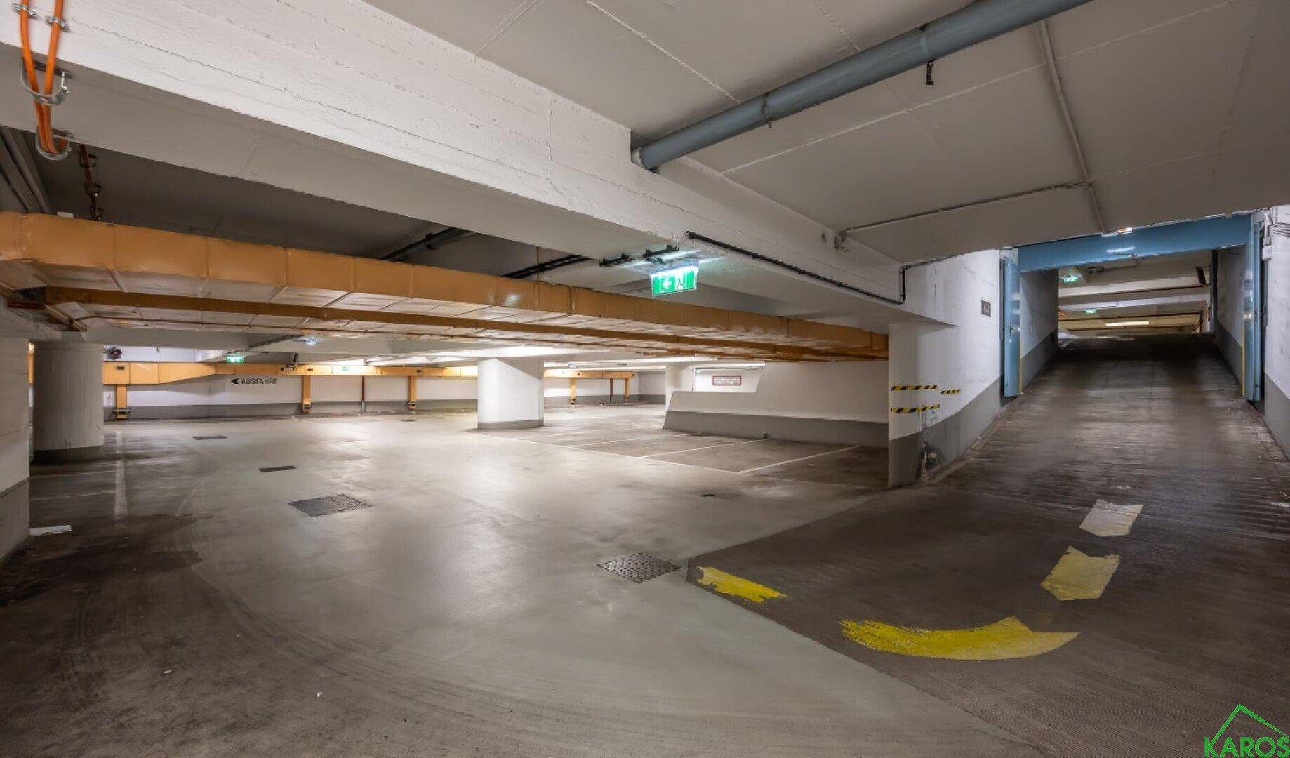 Geräumige Tiefgarage mit vielen Stellplätzen und einer Zufahrtsrampe für Fahrzeuge.