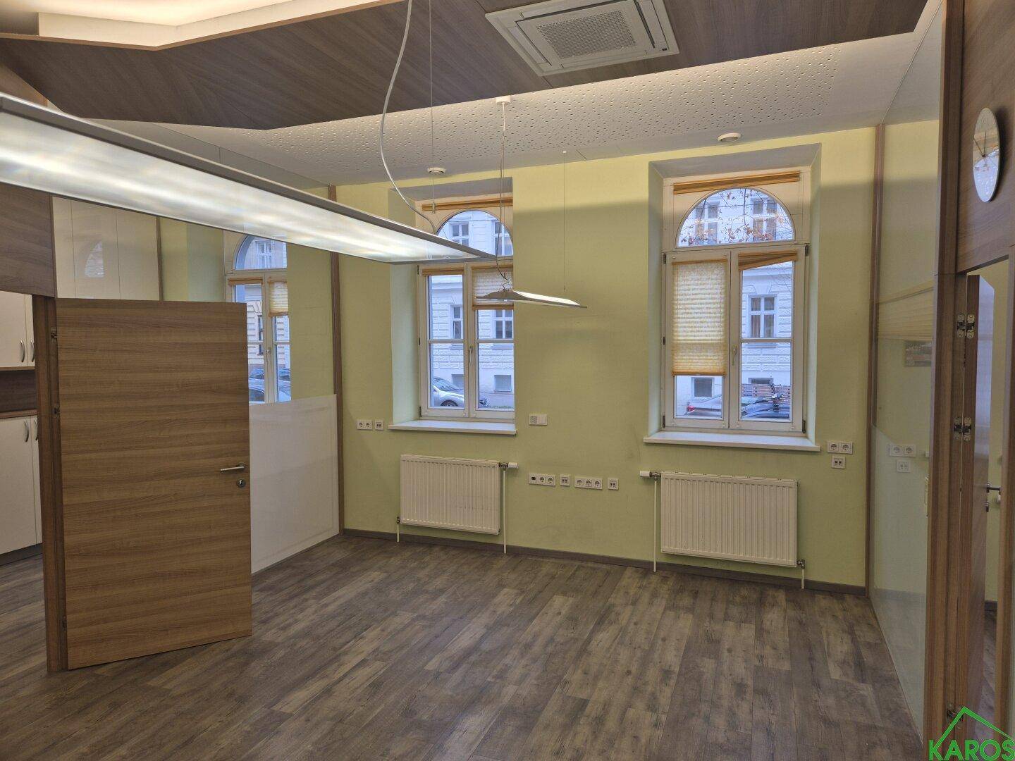 Geräumiger Büroraum mit Holzboden, großen Fenstern und Heizkörpern, in einem Altbau gelegen.