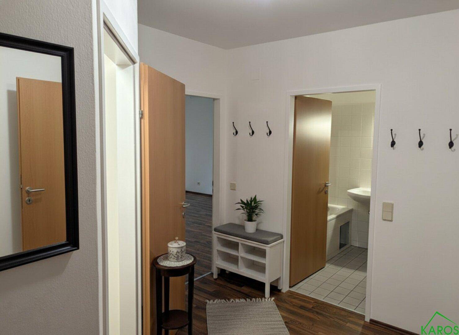 Eingangsbereich mit Garderobe, Spiegel und Zugang zu verschiedenen Zimmern, inklusive Badezimmer.