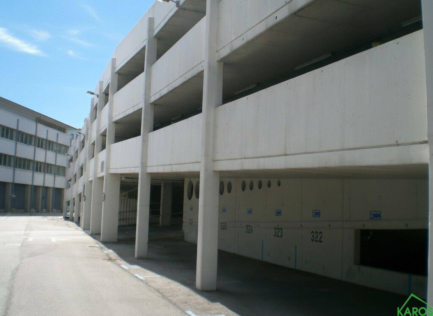 Ansicht eines modernen, mehrstöckigen Parkhauses aus Beton mit nummerierten Parkplätzen und einer geraden Linienführung.