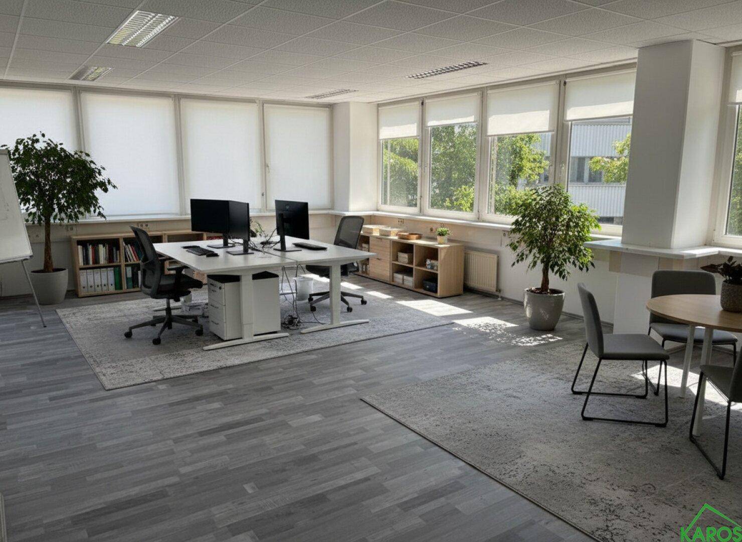 Helles und geräumiges Büro mit mehreren Arbeitsplätzen, großen Fenstern und Blick ins Grüne.