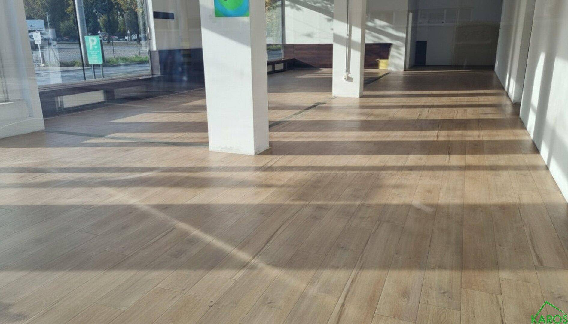 Heller, leerer Gewerberaum mit großen Fenstern, Holzboden und viel natürlichem Licht.