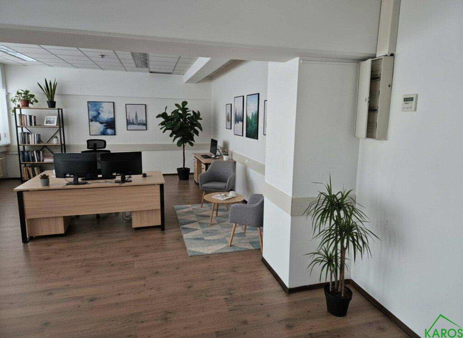 Modern eingerichtetes Büro mit Holzboden, Arbeitsbereichen und einer kleinen Besprechungsecke, ideal für Produktivität.