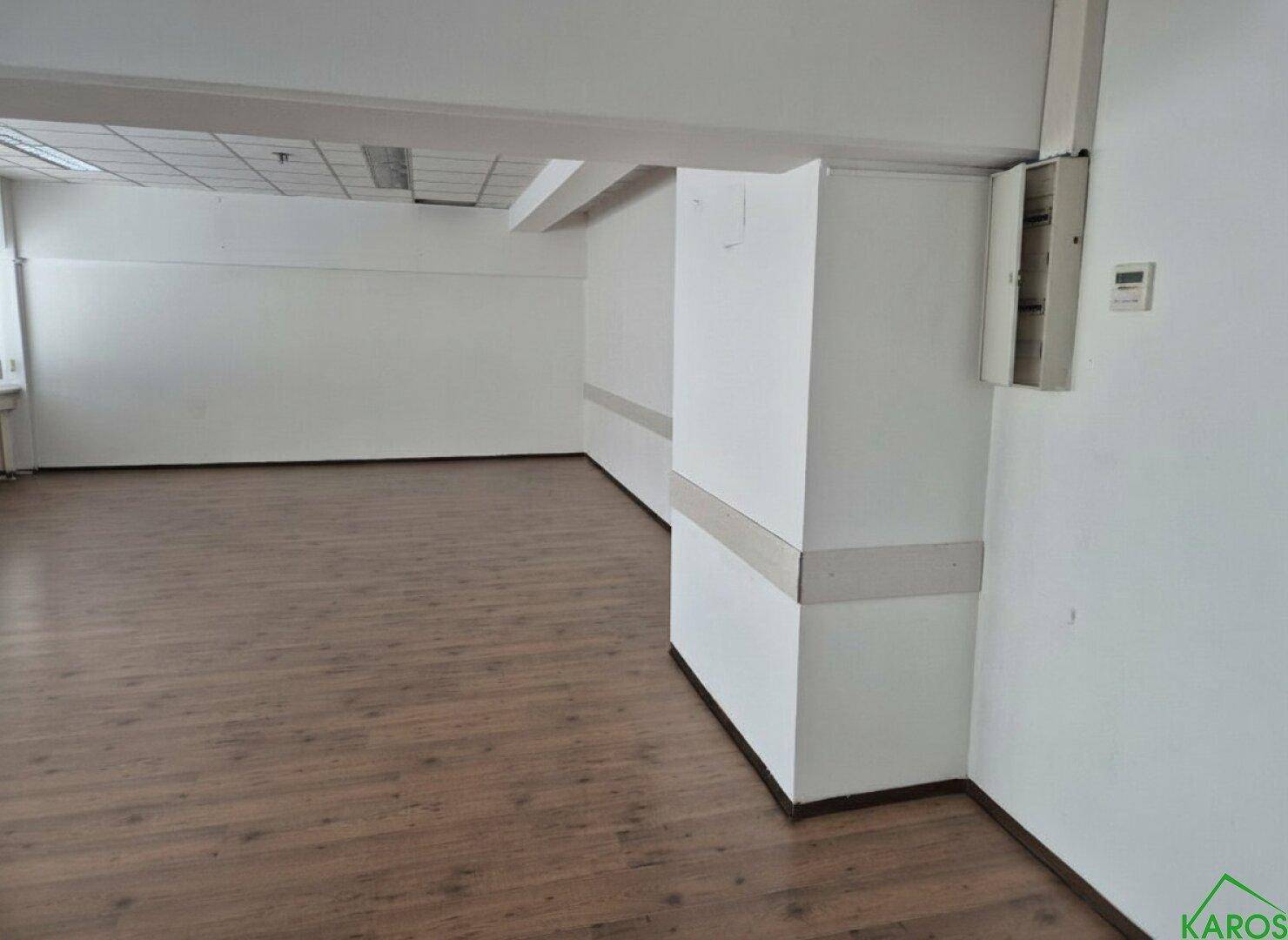 Leeres Büro mit hellem Holzboden und weißen Wänden, bietet eine flexible Fläche für verschiedene Nutzungen.