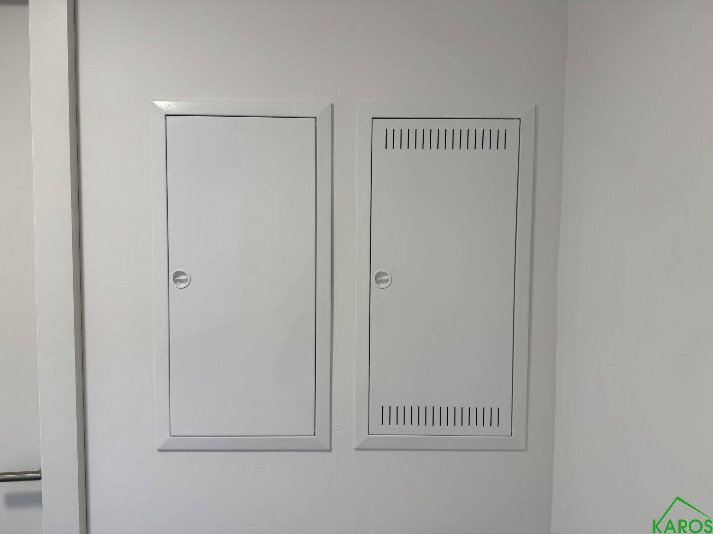 Nahaufnahme von zwei weißen Revisionsklappen an einer hellen Wand, die Zugang zu Installationen bieten.
