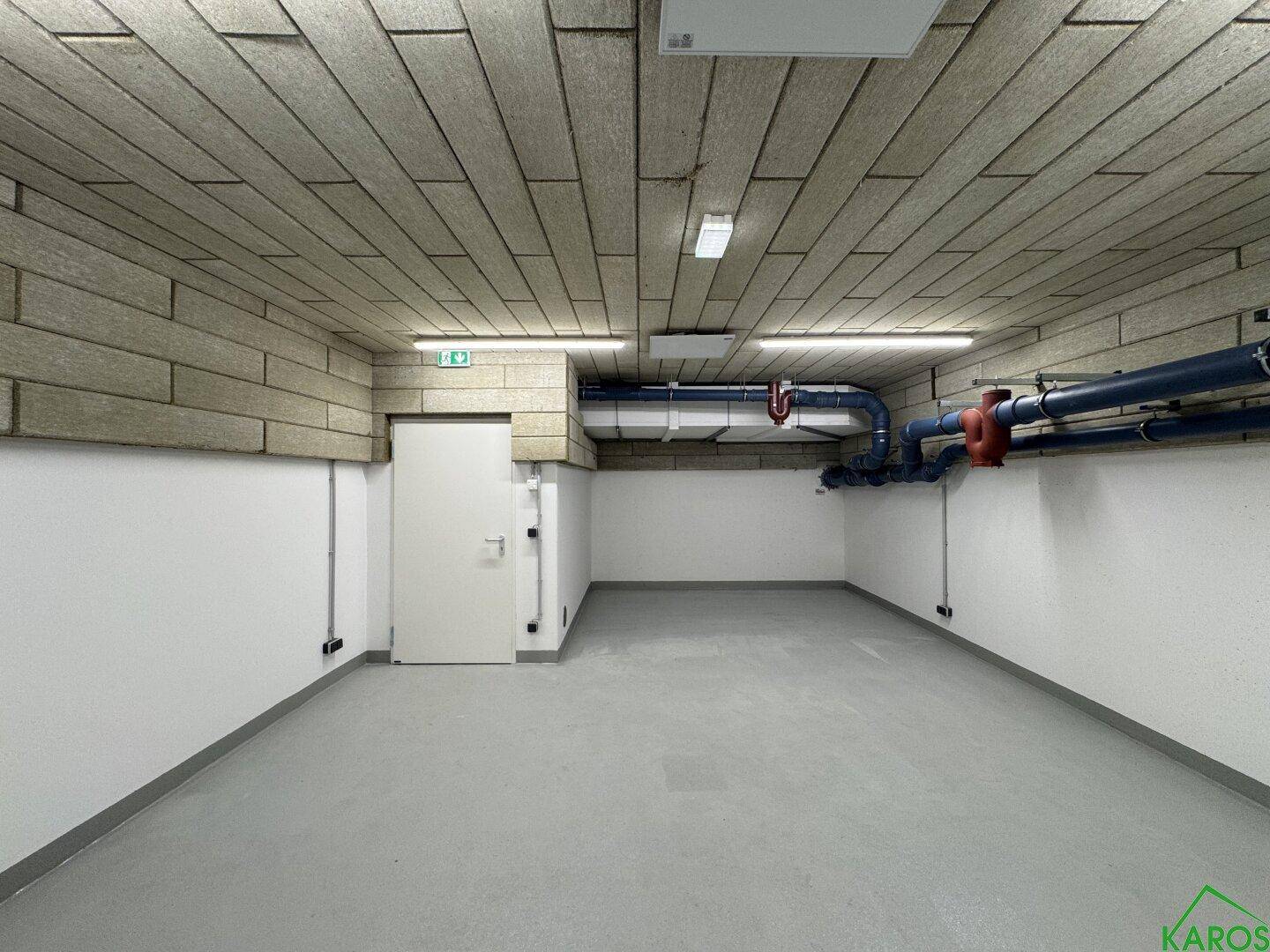 Geräumiger Kellerraum mit funktionaler Ausstattung und unverputzten Deckenplatten in einem Neubau.