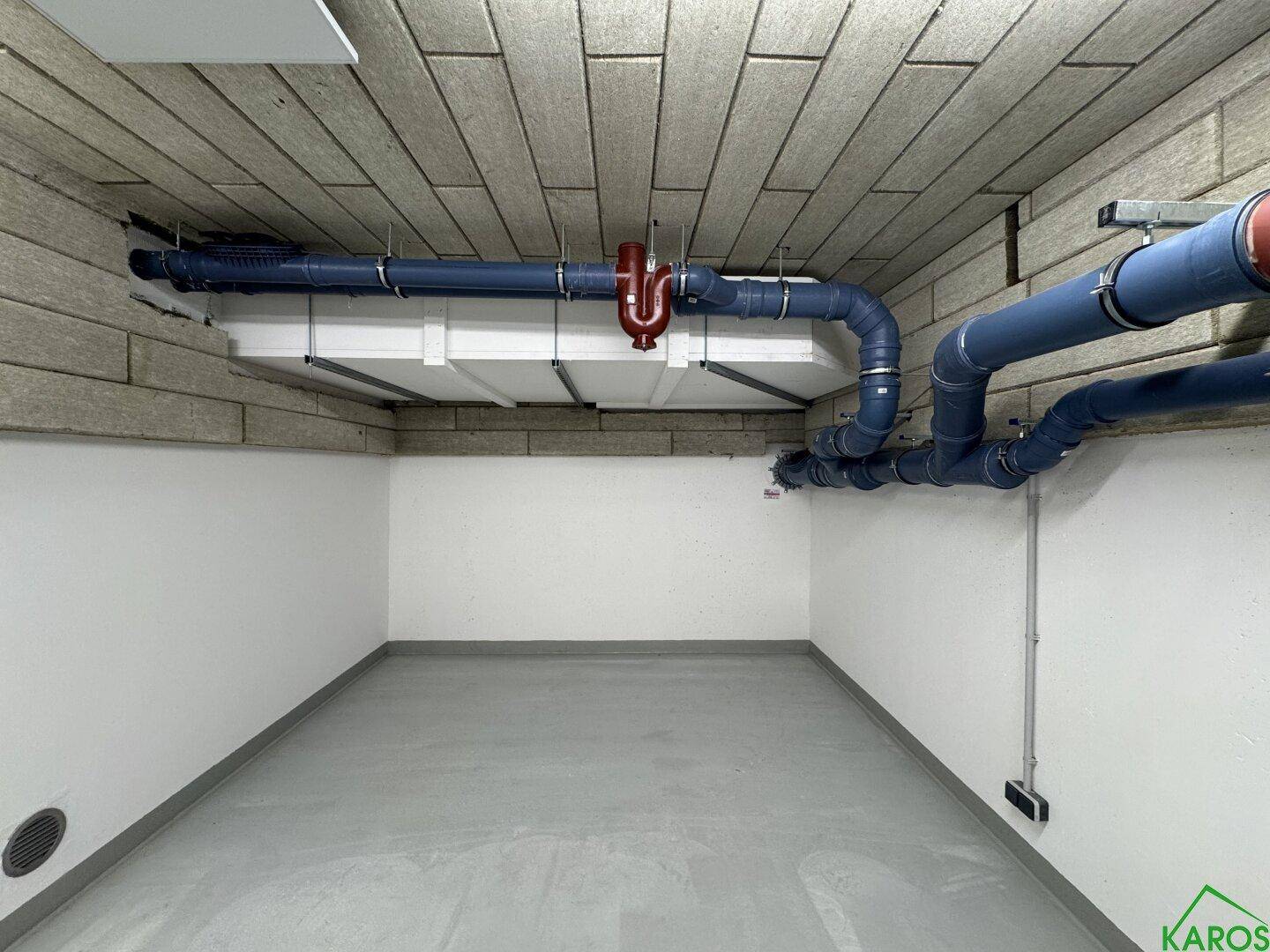 Detailansicht der blauen und roten Versorgungsleitungen an der Decke des Kellerraums in einem Neubau.