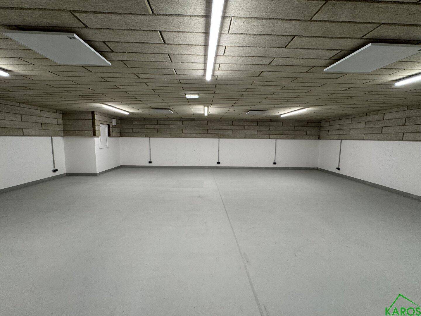 Geräumiger, leerer Lagerraum mit hellem Boden, weißen Wänden und einer strukturierten Decke, gut beleuchtet.